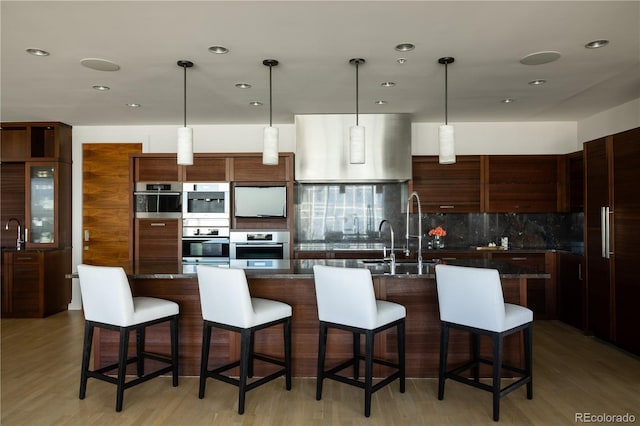 kitchen with tasteful backsplash, an island with sink, and a kitchen bar