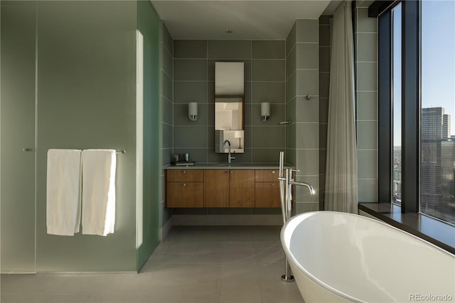 bathroom with a washtub, vanity, and tile patterned flooring