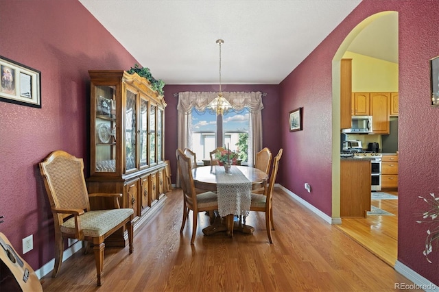 12522 Locust Way, Thornton, CO 80602 - dining room with arched walkways, a chandelier, a textured wall, and light wood-style floors