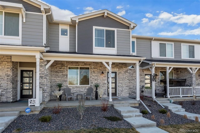 view of property featuring stone siding and a porch