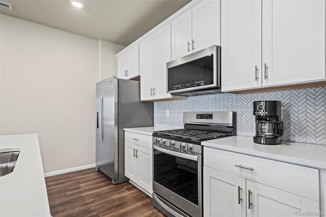 kitchen with dark wood-type flooring, backsplash, white cabinetry, appliances with stainless steel finishes, and light countertops