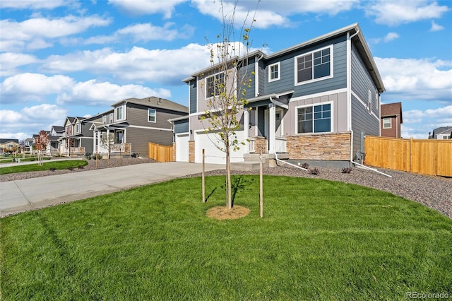 view of front of home with board and batten siding, fence, a front yard, stone siding, and driveway