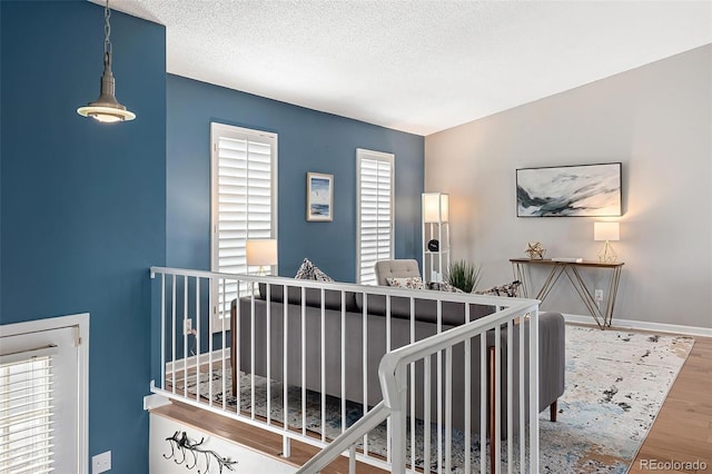 stairway with a textured ceiling, baseboards, and wood finished floors