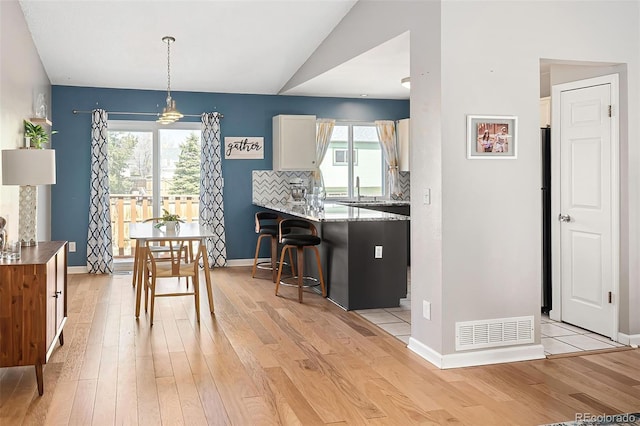dining area featuring light wood-style floors, visible vents, and baseboards