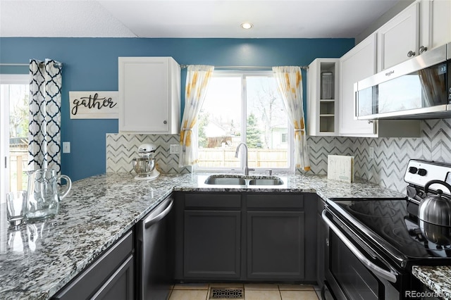 kitchen with a sink, light stone countertops, a wealth of natural light, and stainless steel appliances
