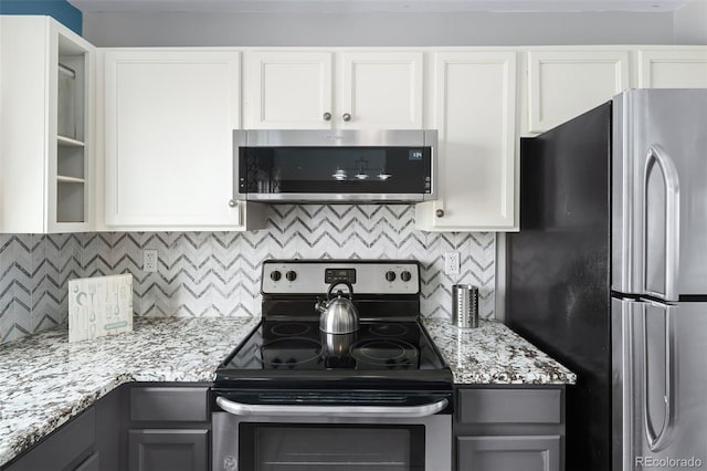 kitchen with backsplash, gray cabinets, light stone counters, and stainless steel appliances