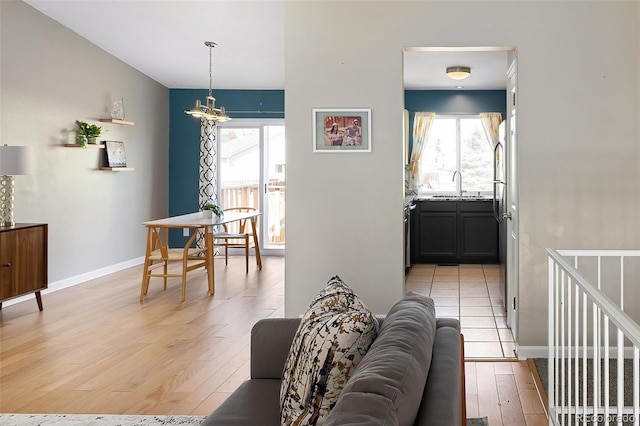 living room featuring a chandelier, light wood-type flooring, and baseboards