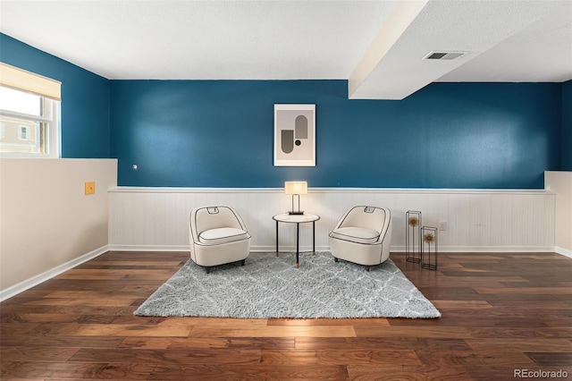 sitting room with visible vents, a wainscoted wall, wood finished floors, and baseboards