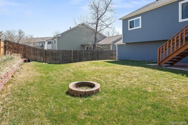 view of yard with an outdoor fire pit, fence, and stairway