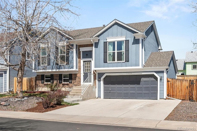 bi-level home featuring an attached garage, board and batten siding, a shingled roof, and fence