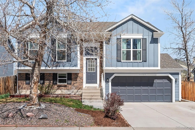 raised ranch featuring board and batten siding, fence, brick siding, and concrete driveway