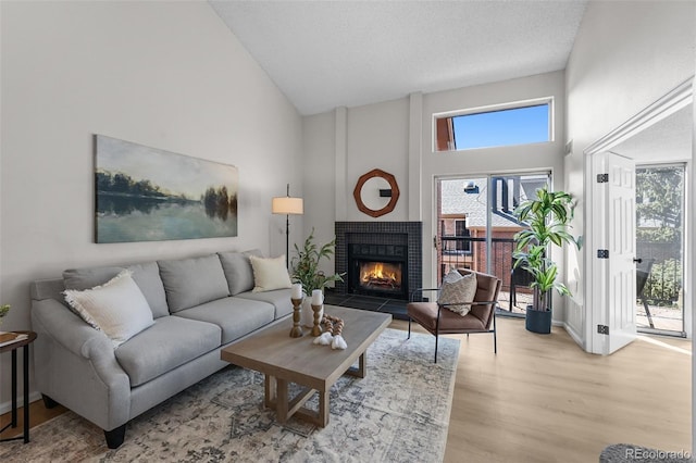 living room with high vaulted ceiling, a fireplace, healthy amount of natural light, wood finished floors, and baseboards