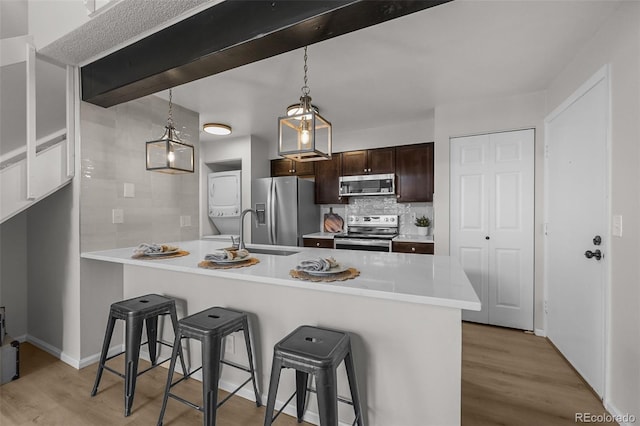 kitchen featuring stainless steel appliances, stacked washer / drying machine, a sink, and a kitchen bar