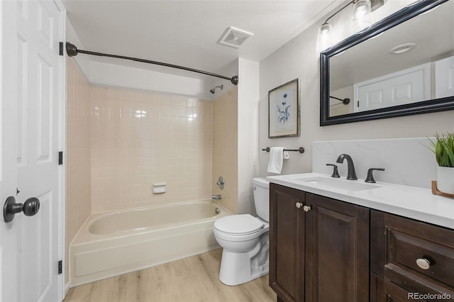 full bath with toilet, wood finished floors, vanity, and washtub / shower combination