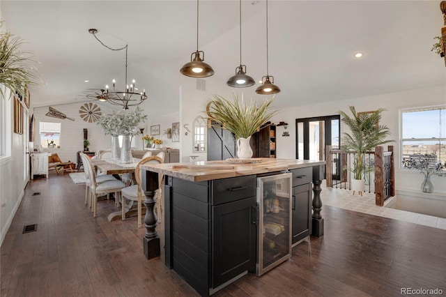 kitchen featuring dark wood-style floors, wine cooler, vaulted ceiling, dark cabinetry, and butcher block countertops
