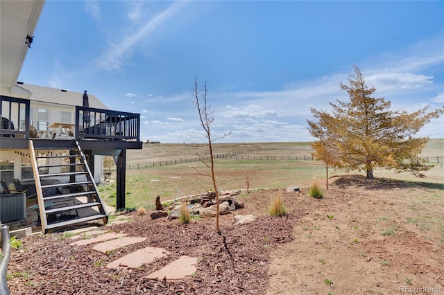 view of yard featuring a wooden deck, stairway, central AC unit, and a rural view