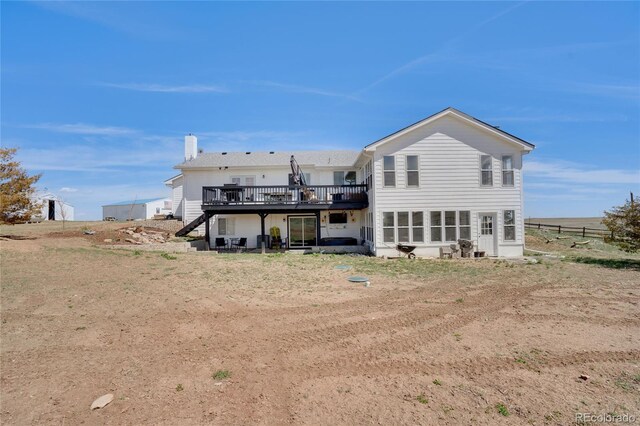 back of house featuring stairway, a chimney, and a deck