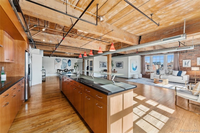 kitchen featuring a sink, light wood-style floors, open floor plan, stainless steel refrigerator with ice dispenser, and dark countertops