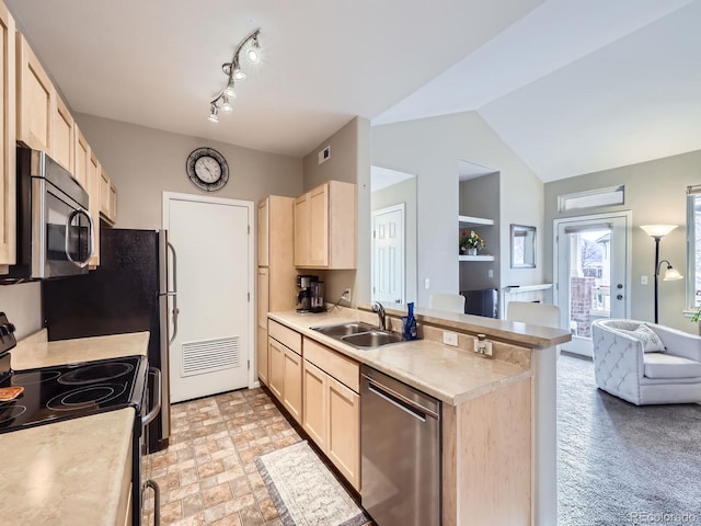 kitchen with a peninsula, light brown cabinets, appliances with stainless steel finishes, and a sink