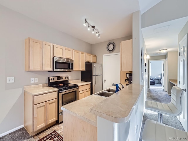 kitchen with stainless steel appliances, light brown cabinets, and a sink