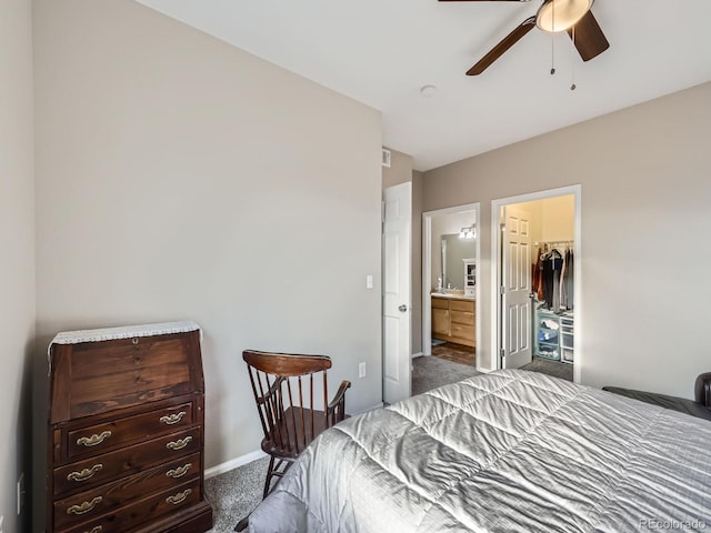 bedroom with a walk in closet, a ceiling fan, carpet flooring, connected bathroom, and baseboards