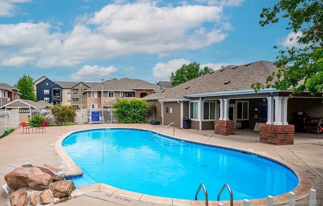 pool with a patio, fence, and a residential view