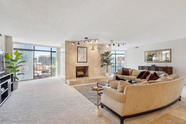 living room with a textured ceiling, expansive windows, rail lighting, and a tiled fireplace