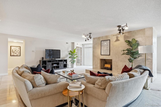 living room with a fireplace, track lighting, a textured ceiling, and light tile patterned floors