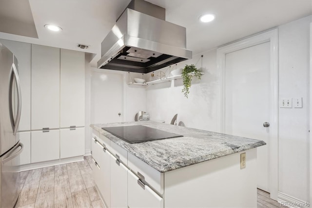 kitchen with light hardwood / wood-style flooring, black electric cooktop, white cabinetry, island exhaust hood, and stainless steel refrigerator