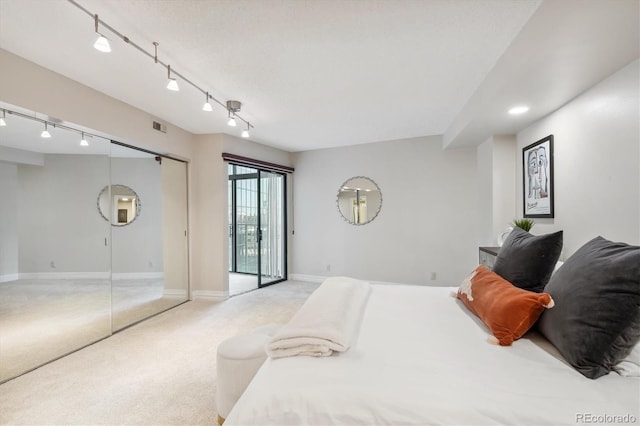 carpeted bedroom with rail lighting and a closet