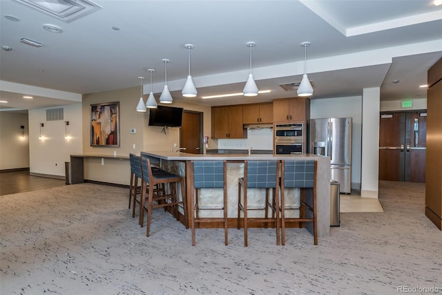 kitchen featuring sink, stainless steel appliances, kitchen peninsula, decorative light fixtures, and a breakfast bar