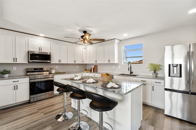 1134 Buffalo Run Rd, Calhan, CO 80808 - kitchen with stainless steel appliances, a sink, recessed lighting, white cabinetry, and a kitchen breakfast bar