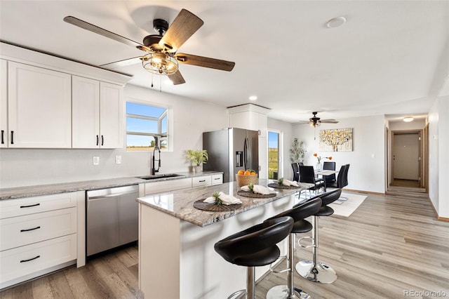 1134 Buffalo Run Rd, Calhan, CO 80808 - kitchen featuring a sink, stainless steel appliances, a ceiling fan, a kitchen bar, and white cabinets