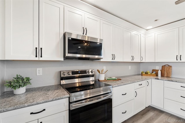 1134 Buffalo Run Rd, Calhan, CO 80808 - kitchen featuring appliances with stainless steel finishes, white cabinetry, light wood-type flooring, and light stone counters