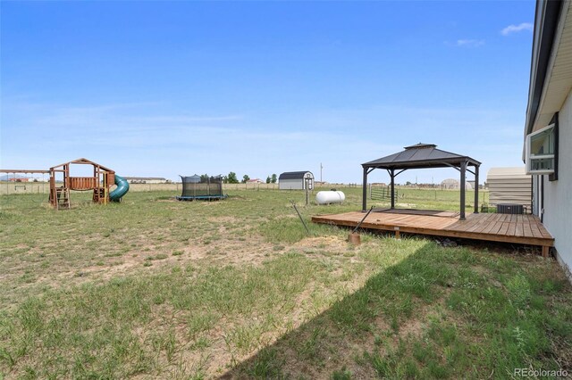 1134 Buffalo Run Rd, Calhan, CO 80808 - view of green lawn featuring a trampoline, a playground, a gazebo, a wooden deck, and central AC unit