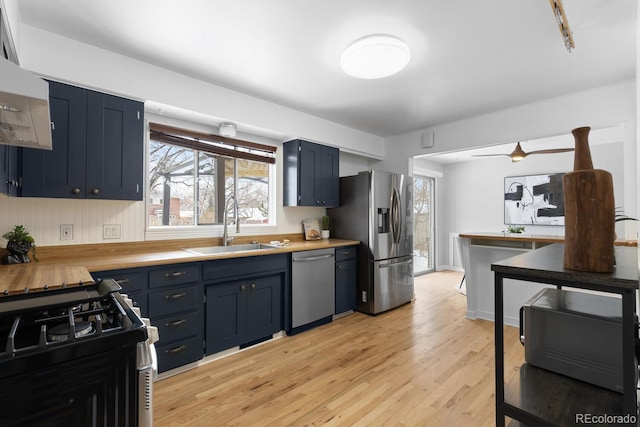 kitchen featuring sink, stainless steel appliances, blue cabinets, and light hardwood / wood-style floors