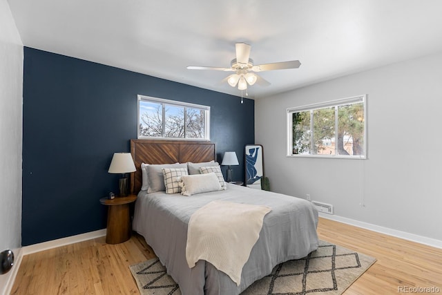 bedroom featuring ceiling fan, multiple windows, and light wood-type flooring