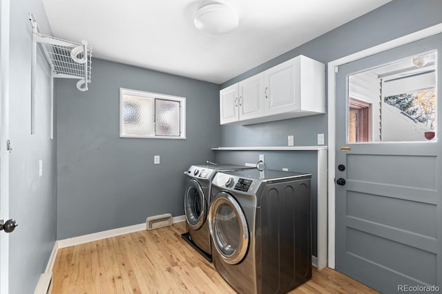 laundry area with cabinets, separate washer and dryer, a baseboard radiator, and light wood-type flooring