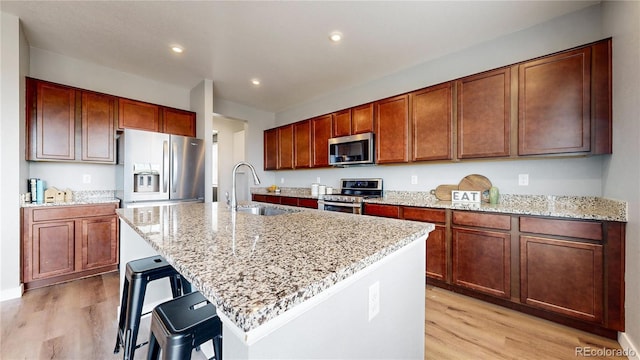 kitchen with a breakfast bar, sink, stainless steel appliances, and an island with sink