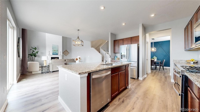 kitchen featuring a kitchen island with sink, sink, light wood-type flooring, and appliances with stainless steel finishes