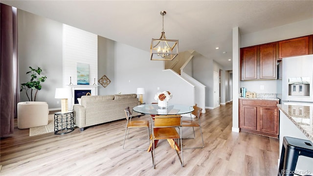 dining area featuring a chandelier, a large fireplace, and light hardwood / wood-style floors