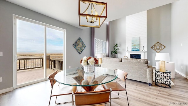 dining space with a large fireplace, light hardwood / wood-style floors, and a notable chandelier