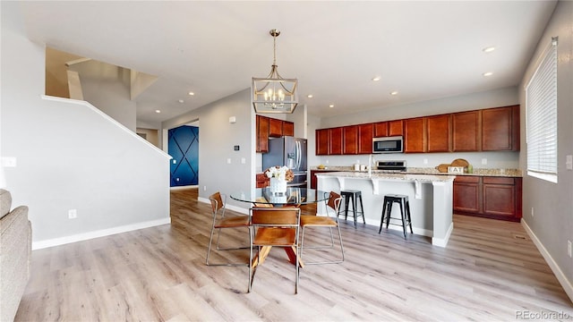 kitchen featuring light stone countertops, hanging light fixtures, a kitchen breakfast bar, a center island with sink, and appliances with stainless steel finishes