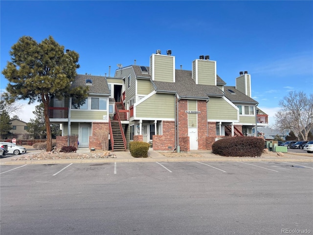 view of property with stairs and uncovered parking