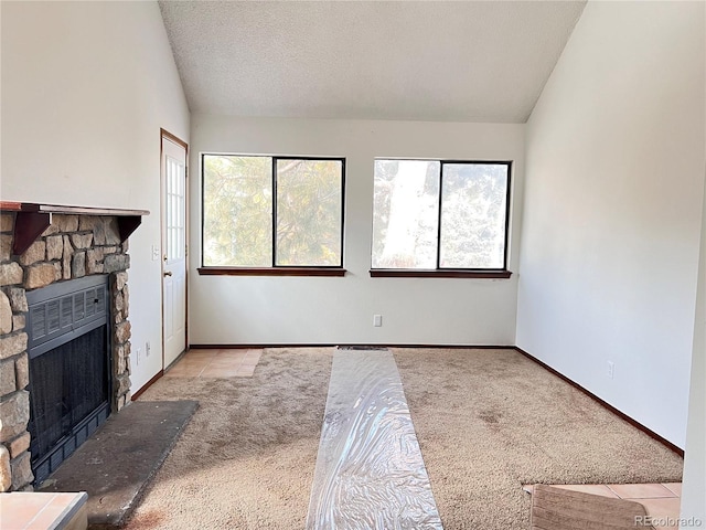 interior space with light carpet, a textured ceiling, a stone fireplace, and lofted ceiling