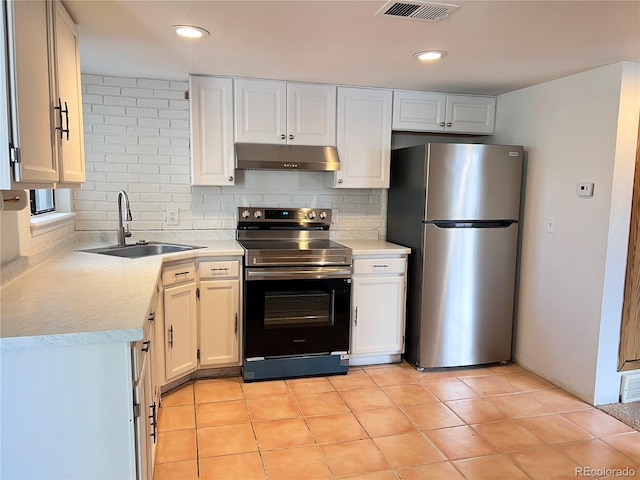 kitchen with light countertops, appliances with stainless steel finishes, a sink, and under cabinet range hood