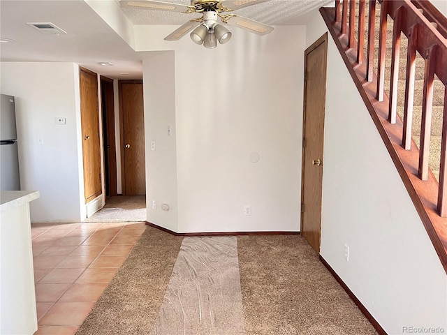 empty room with visible vents, stairway, a ceiling fan, light tile patterned flooring, and baseboards