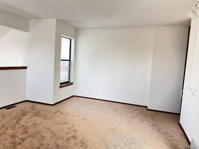 carpeted empty room with visible vents, a textured ceiling, and baseboards