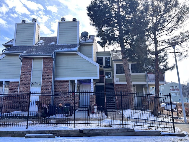 view of front of property with a fenced front yard, a chimney, a shingled roof, and brick siding