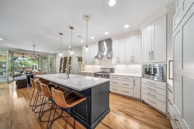 581 Garfield St, Denver, CO 80206 - kitchen with wall chimney exhaust hood, stainless steel microwave, recessed lighting, a kitchen bar, and light countertops